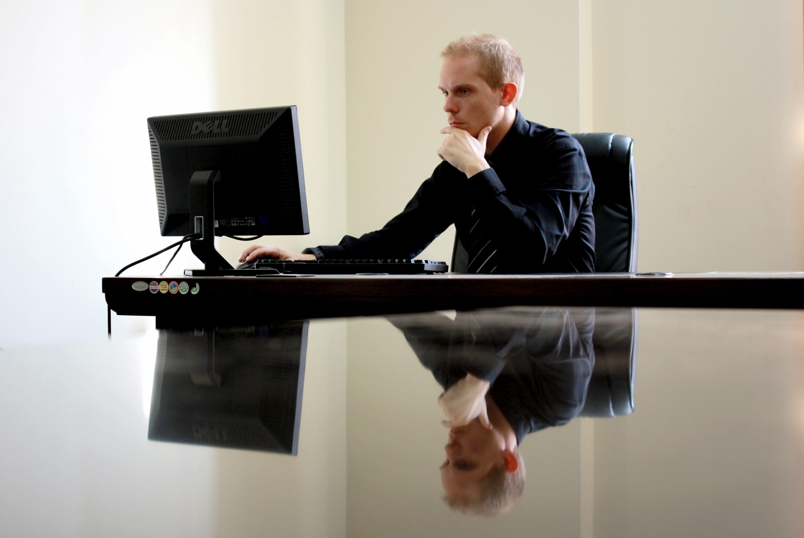 Mężczyzna pracujący na komputerze przy czarnym stole w biurze